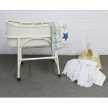 Lloyd loom white bassinet on a white painted stand, together with some bedding and baby shawls.