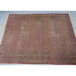 Large Afghan style carpet, the worn red field with an allover repeating pattern within multiple