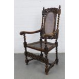 Oak open armchair with figural carved top rail over a caned back and seat with barley twist