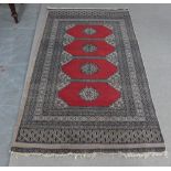 Pakistan rug, red field with four central medallions within multiple geometric borders, 162 x 96cm