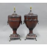 A pair of stained wooden urn vases with domed covers and brass finials, on brass claw and ball feet,