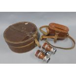 A pair of opera glasses in a brown leather case and a circular brown leather case containing Gents