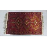 North Afghanistan rug, red field with three hooked lozenges within flowerhead borders, 112 x 70cm