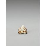 KOGYOKU: A TOKYO-SCHOOL STAINED IVORY NETSUKE OF HOTEI READING A BOOK