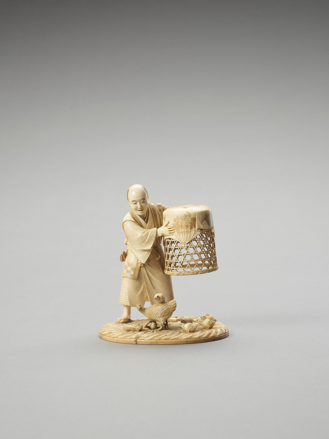 MUNEHIRO: AN IVORY OKIMONO OF A MAN WITH CHICKENS