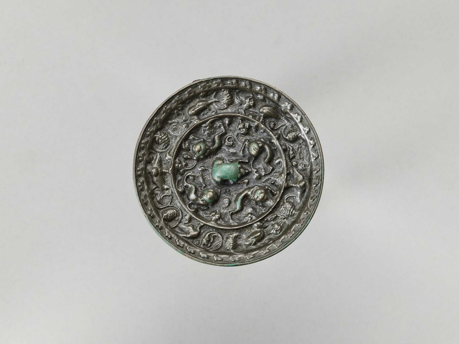 A BRONZE ‘LION AND GRAPEVINE’ MIRROR, FIVE DYNASTIES