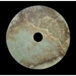 AN EXCEPTIONALLY LARGE PALE GREEN AND RUSSET JADE BI DISC, EARLY BRONZE AGE