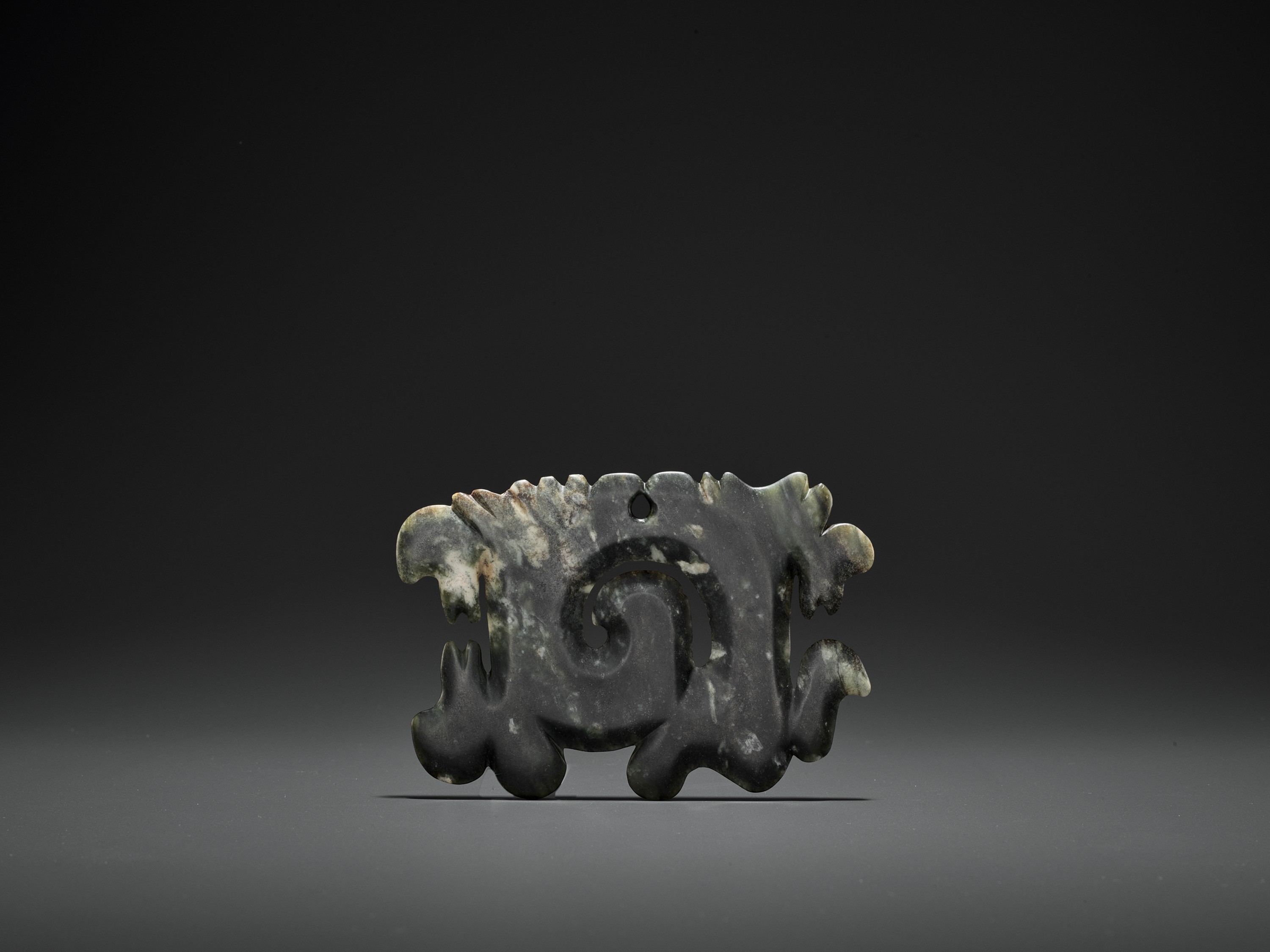 A DARK GREEN JADE OPENWORK 'CLOUD-SCROLL' PENDANT, GOUYUN, HONGSHAN CULTURE