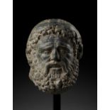 A LIFE-SIZED HEAVY GRAY SCHIST HEAD OF HERACLES, GANDHARA, 4TH-5TH CENTURY