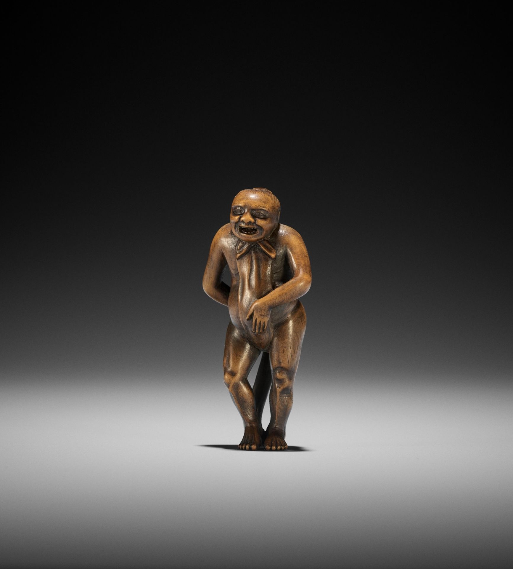 A WOOD NETSUKE OF A NAKED MAN TYING HIS FUNDOSHI