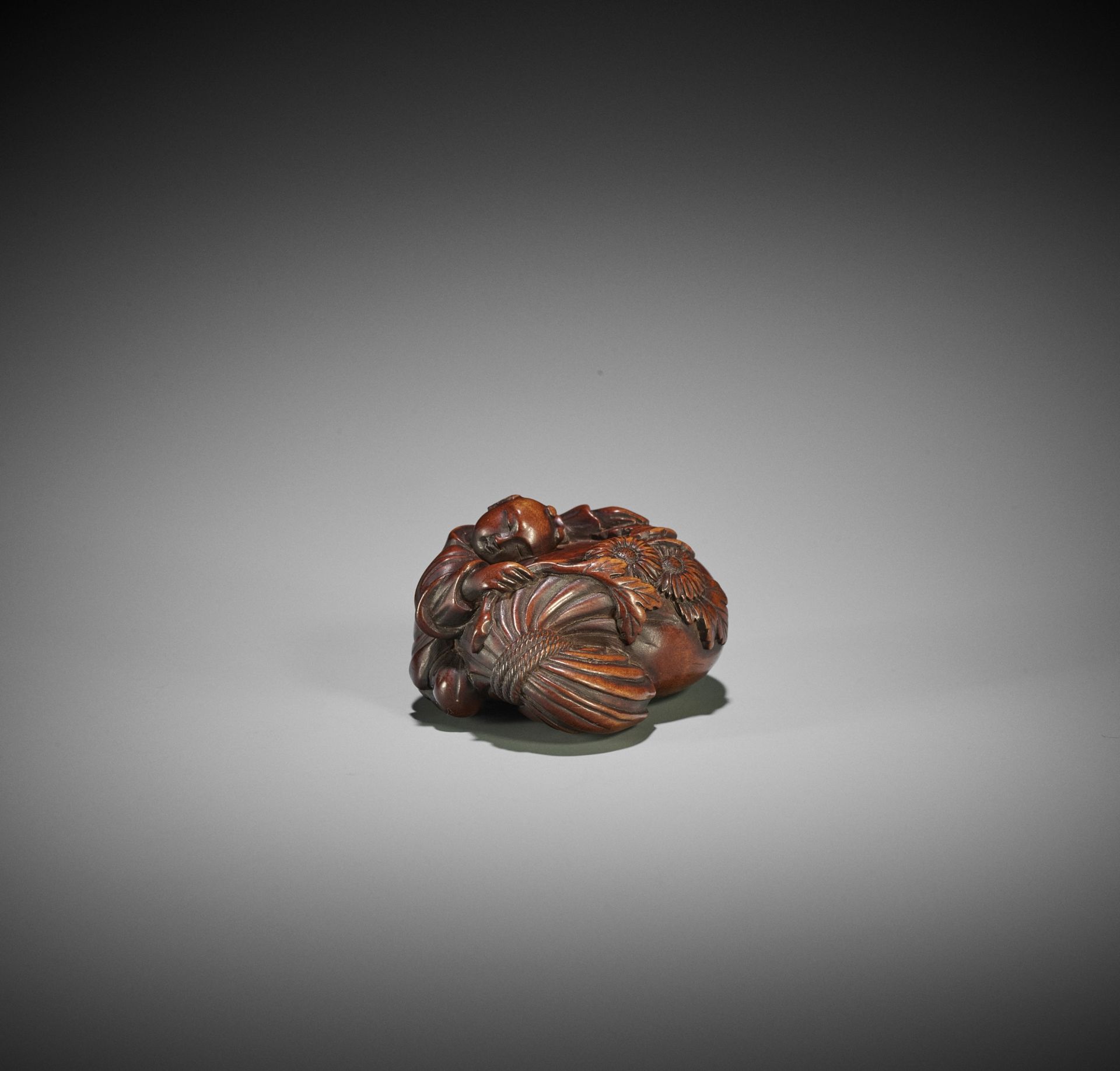 AN EARLY WOOD NETSUKE OF A KARAKO WITH KIKU FLOWER AND TREASURE SACK