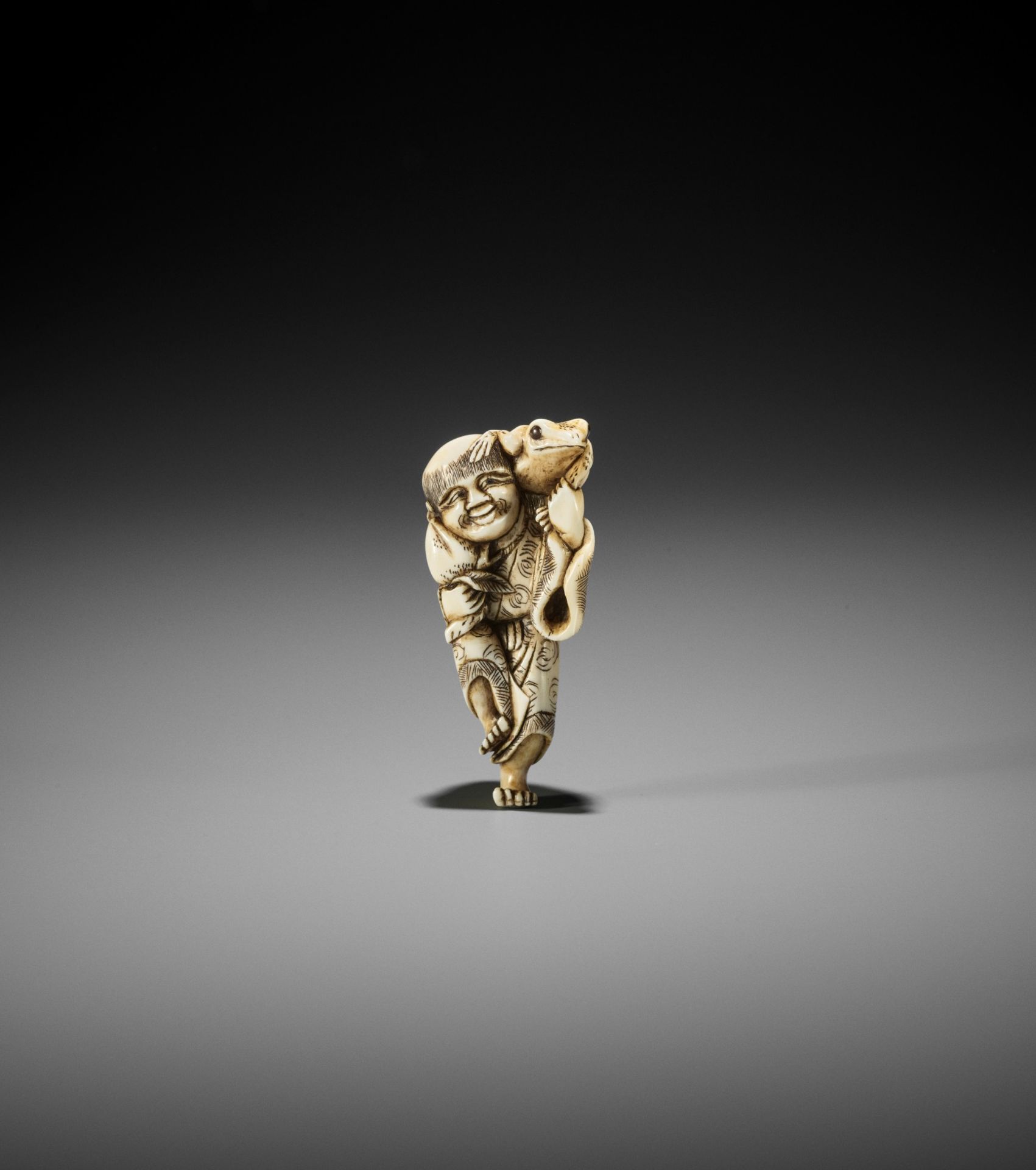 YOSHINAGA: AN IVORY NETSUKE OF GAMA SENNIN WITH A PEACH AND HIS THREE-LEGGED TOAD