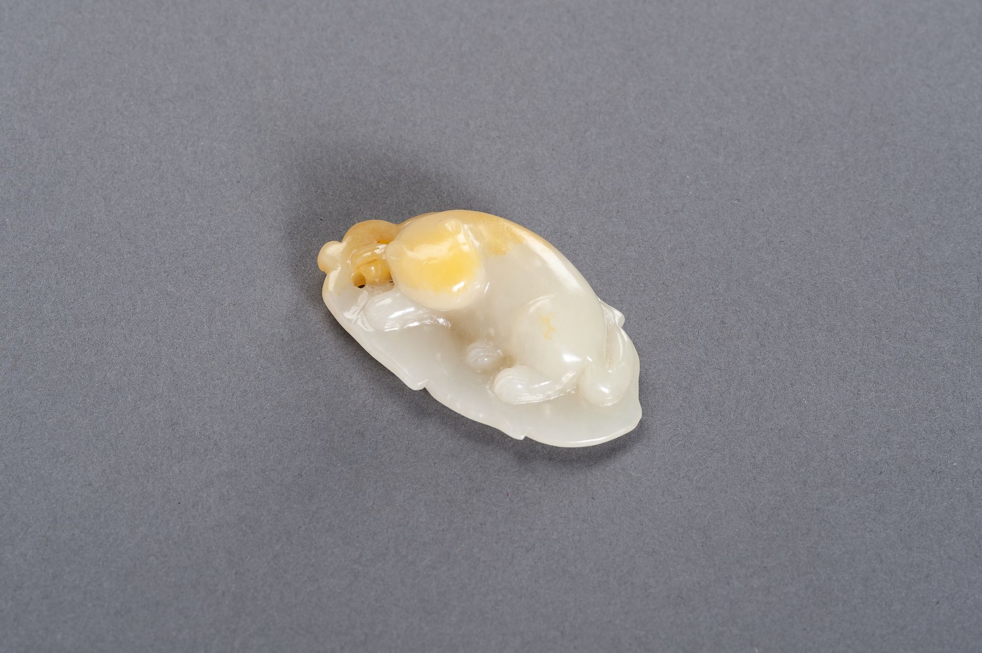 A CELADON AND YELLOW JADE 'CAT ON LEAF' PENDANT, LATE QING TO REPUBLIC