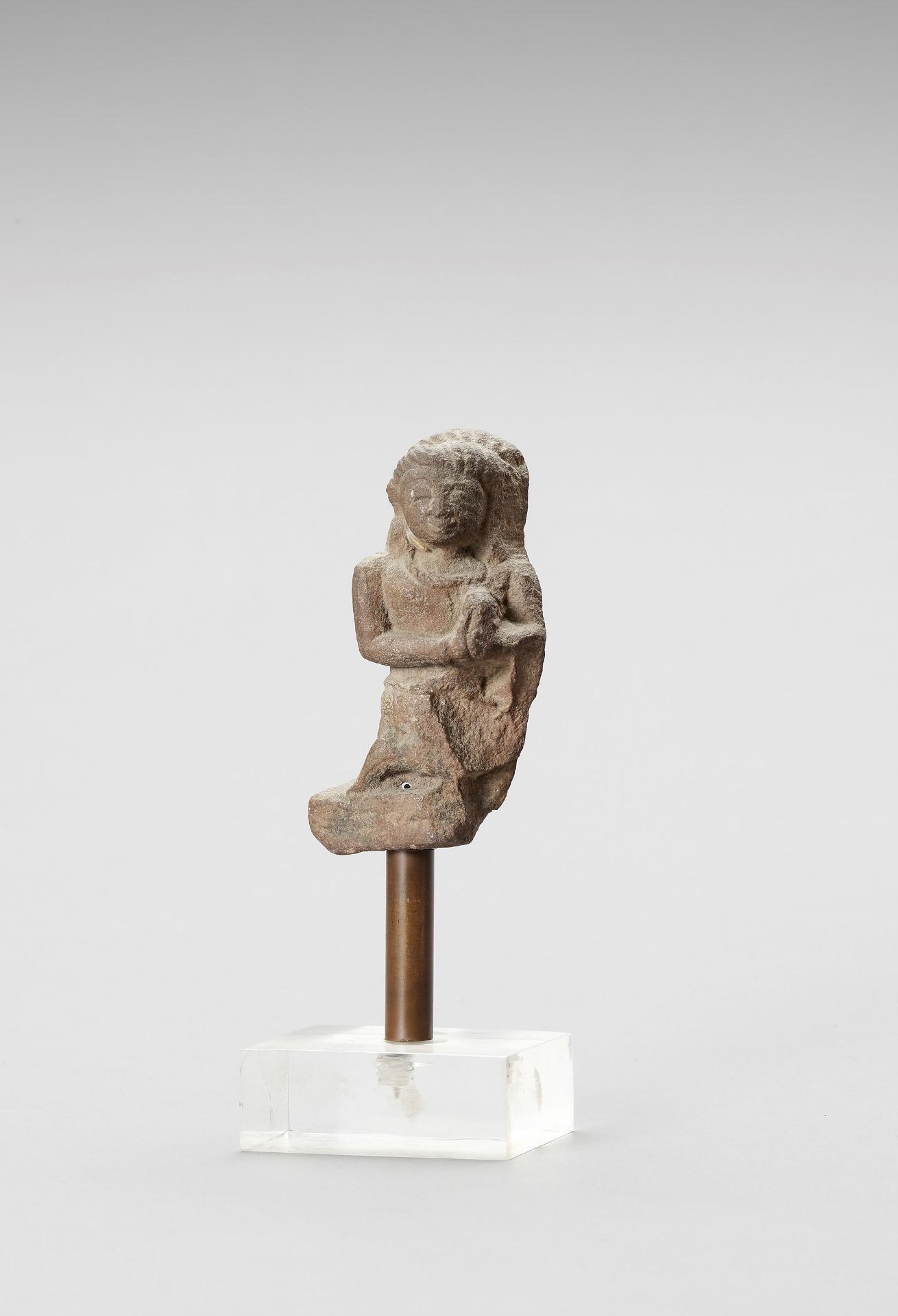 AN INDIAN RED SANDSTONE FRAGMENT DEPICTING A FEMALE WORSHIPPER