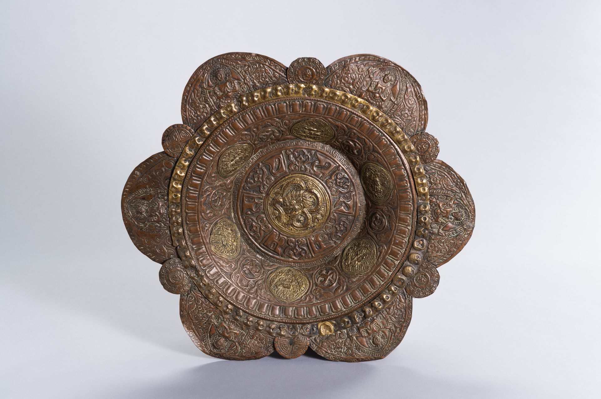 A LARGE COPPER REPOUSSE ALMS DISH