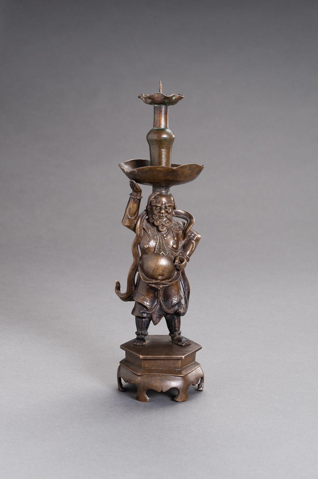 A BRONZE 'FOREIGNER' CANDLESTICK