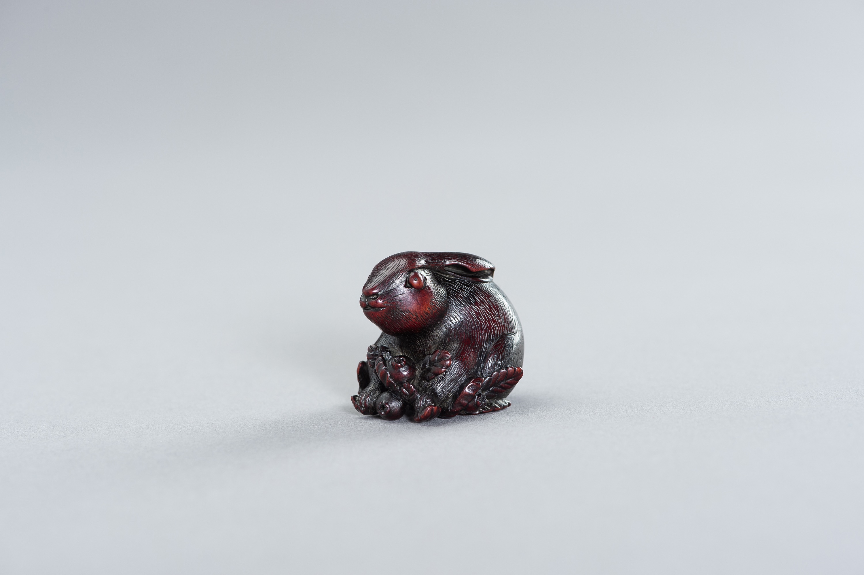 A WOOD NETSUKE OF A HARE WITH BIWA FRUIT