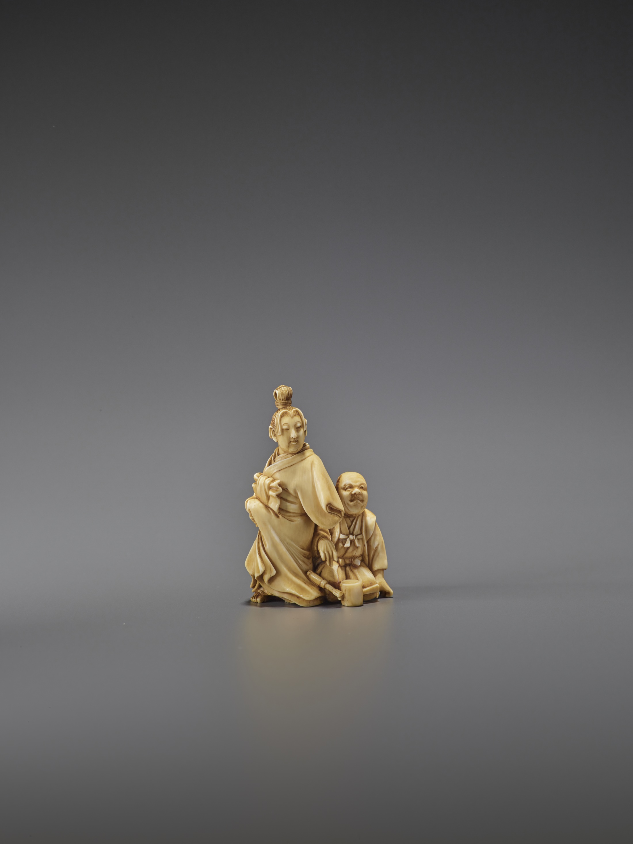 MUNENARI: A RARE IVORY NETSUKE OF A NETSUKE CARVER