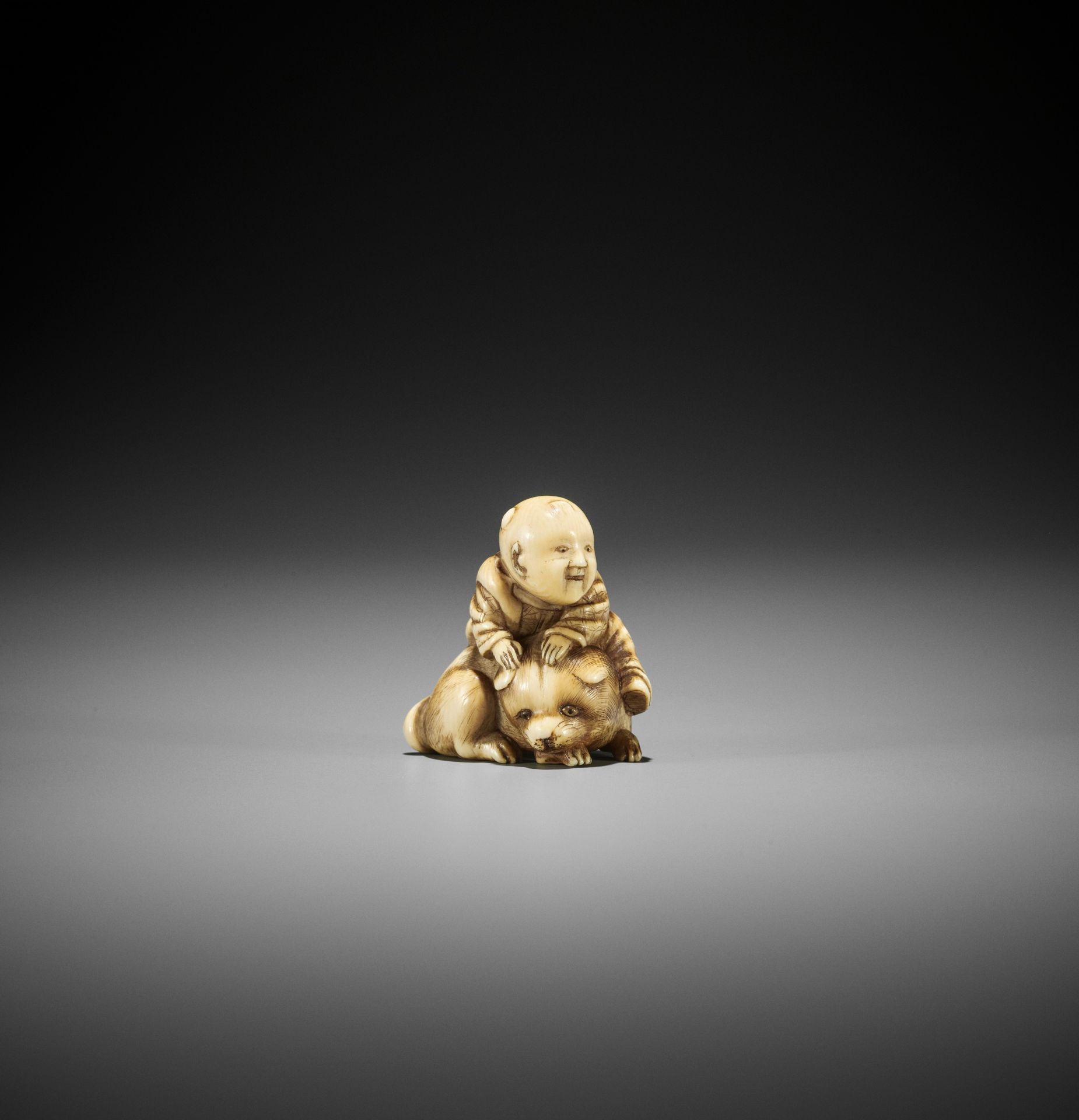 AN OSAKA SCHOOL IVORY NETSUKE OF A KARAKO ON A PUPPY