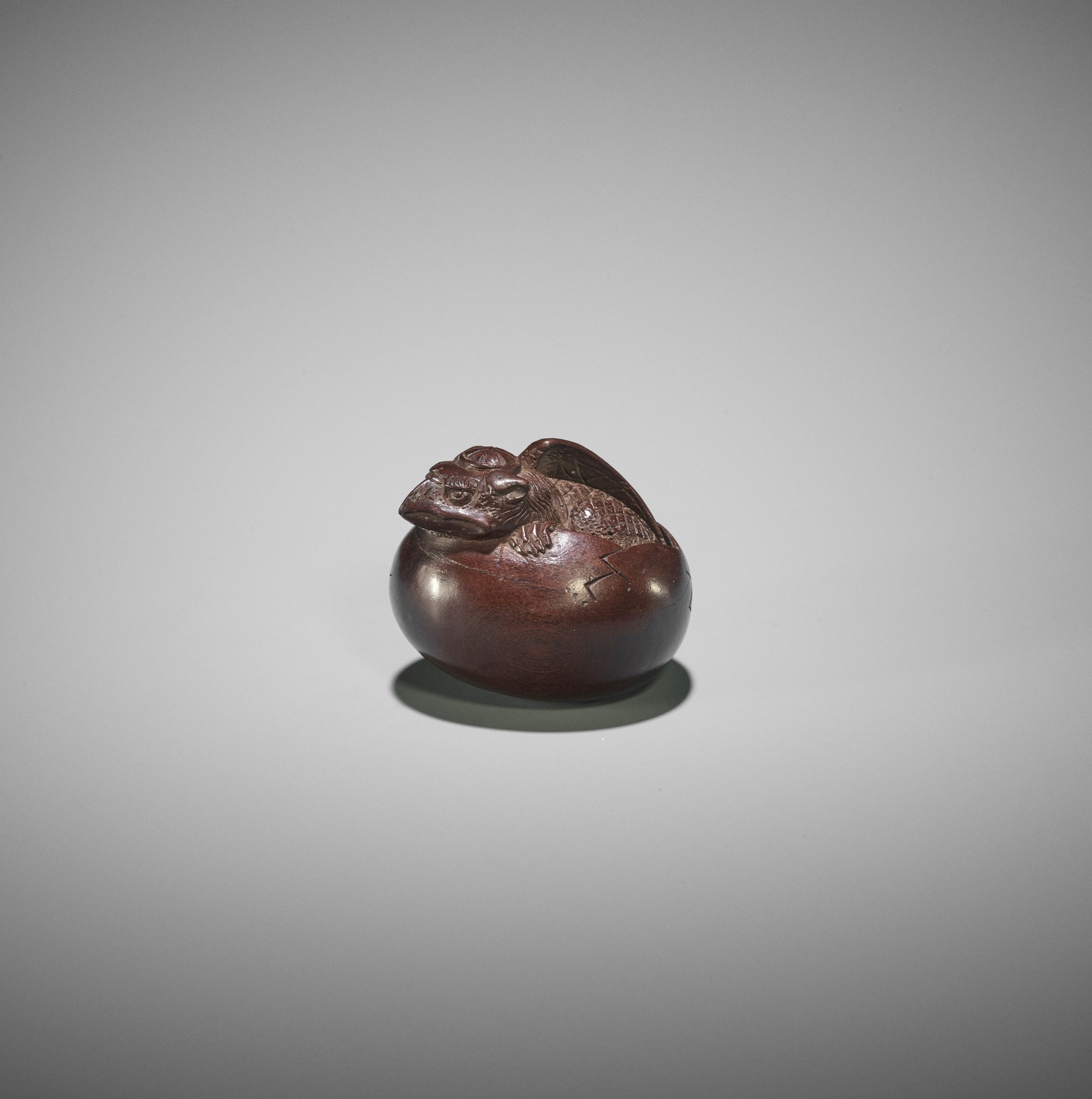 DEME MASAHIDE: A WOOD NETSUKE OF A HATCHING TENGU (TENGU NO TOMAGO)