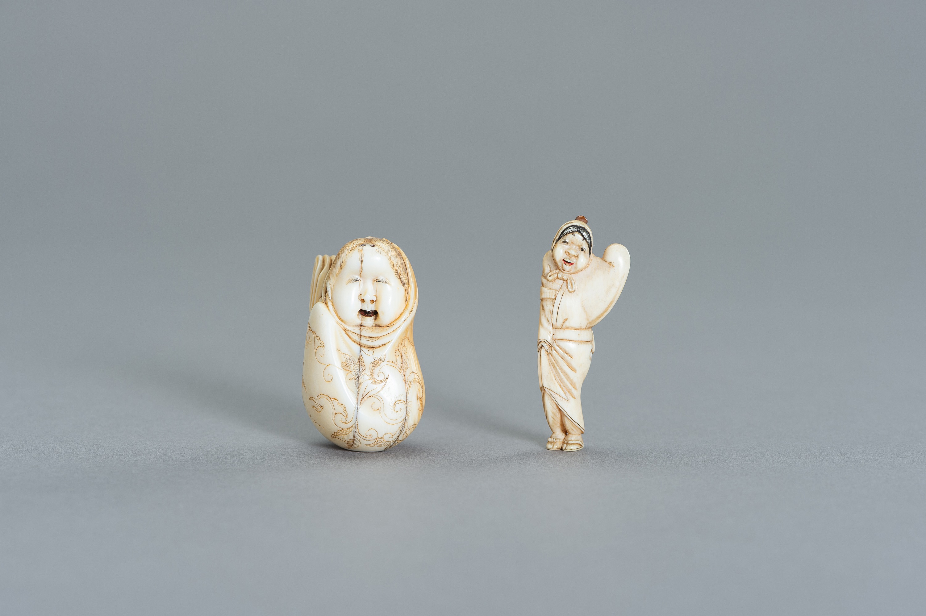 A GROUP OF TWO IVORY NETSUKE OF OKAME