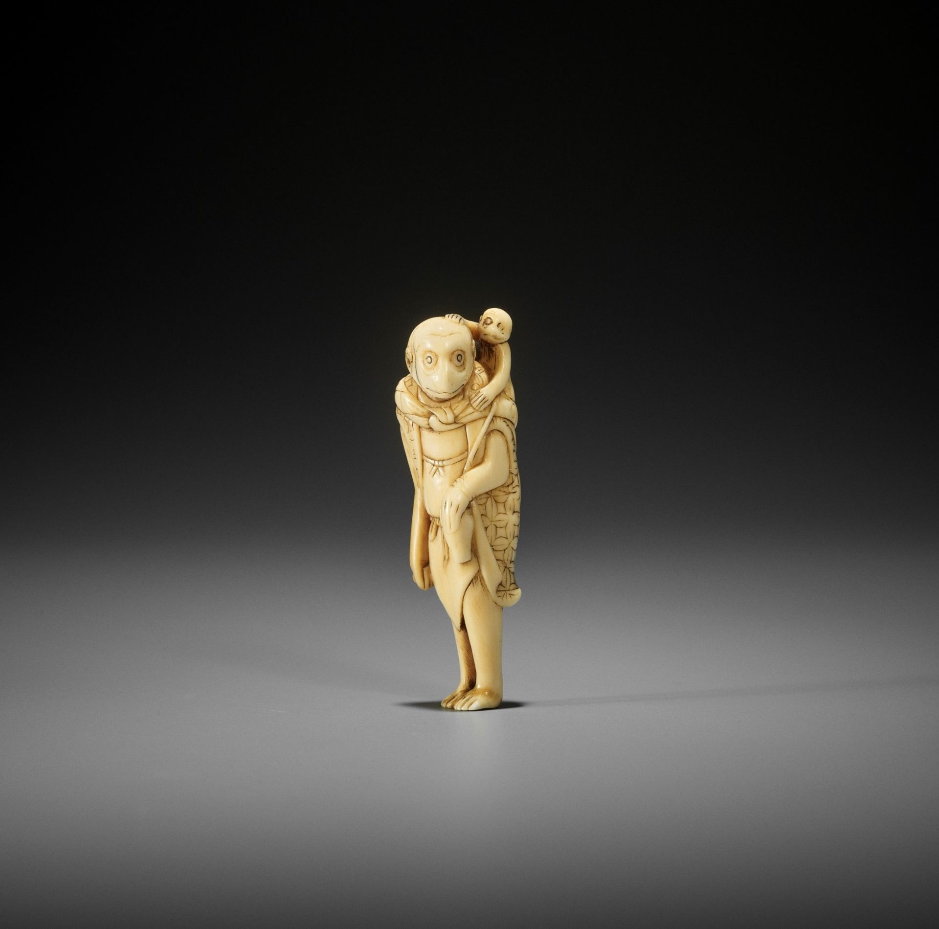 AN UNUSUAL AND EARLY IVORY NETSUKE OF A MONKEY AS A SARUMAWASHI