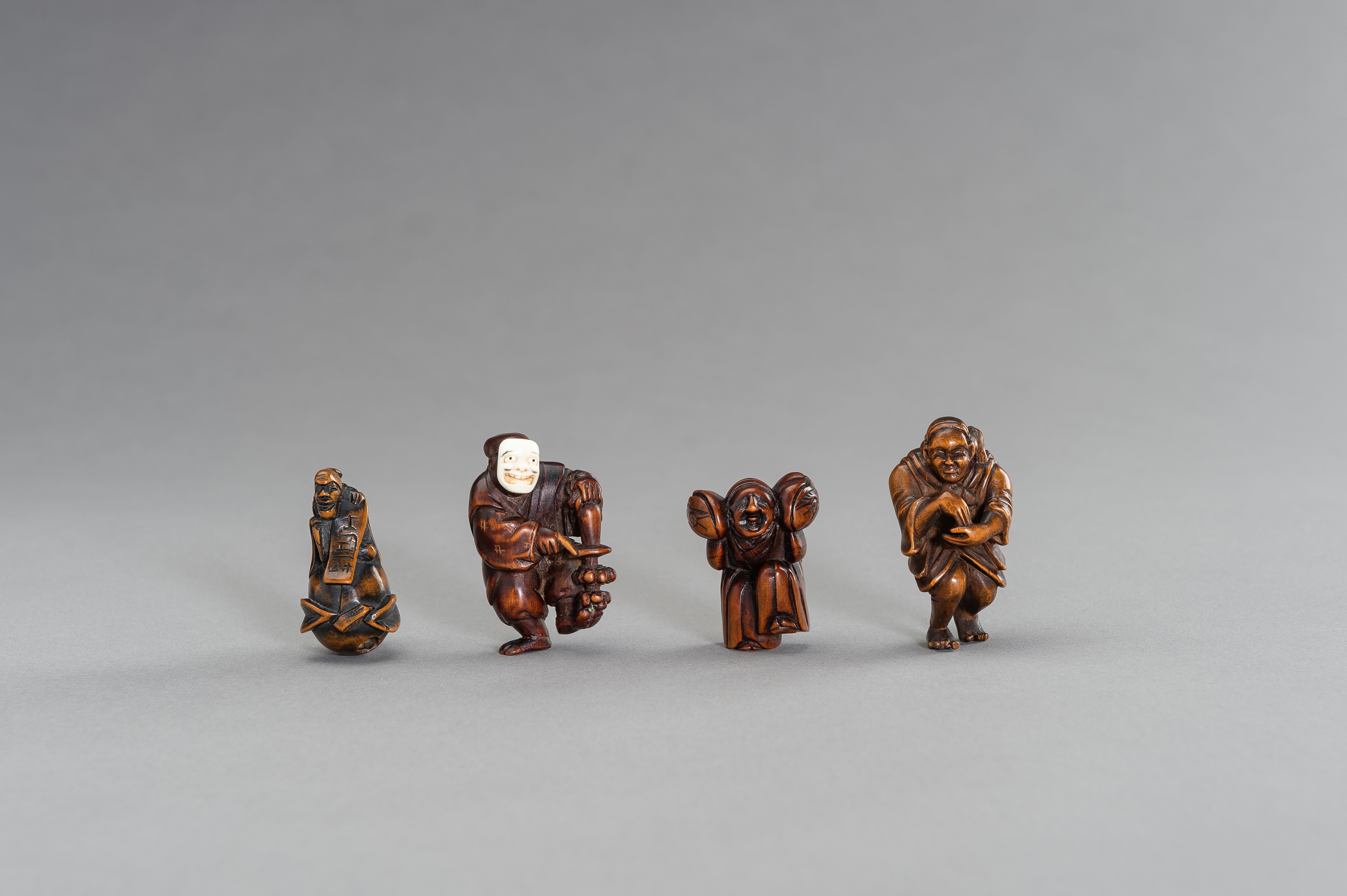 A GROUP OF FOUR FIGURAL WOOD NETSUKE