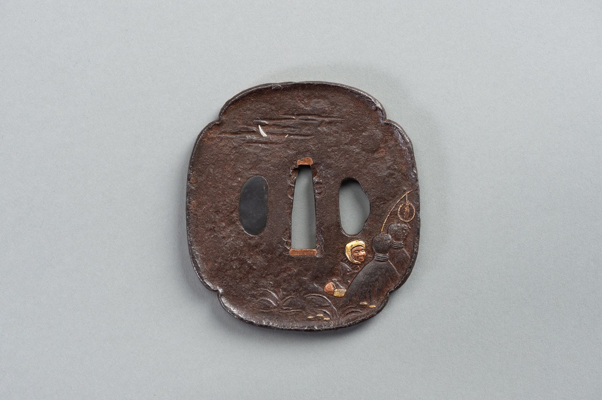 AN INLAID IRON TSUBA WITH A MAN TRYING TO CATCH A FOX