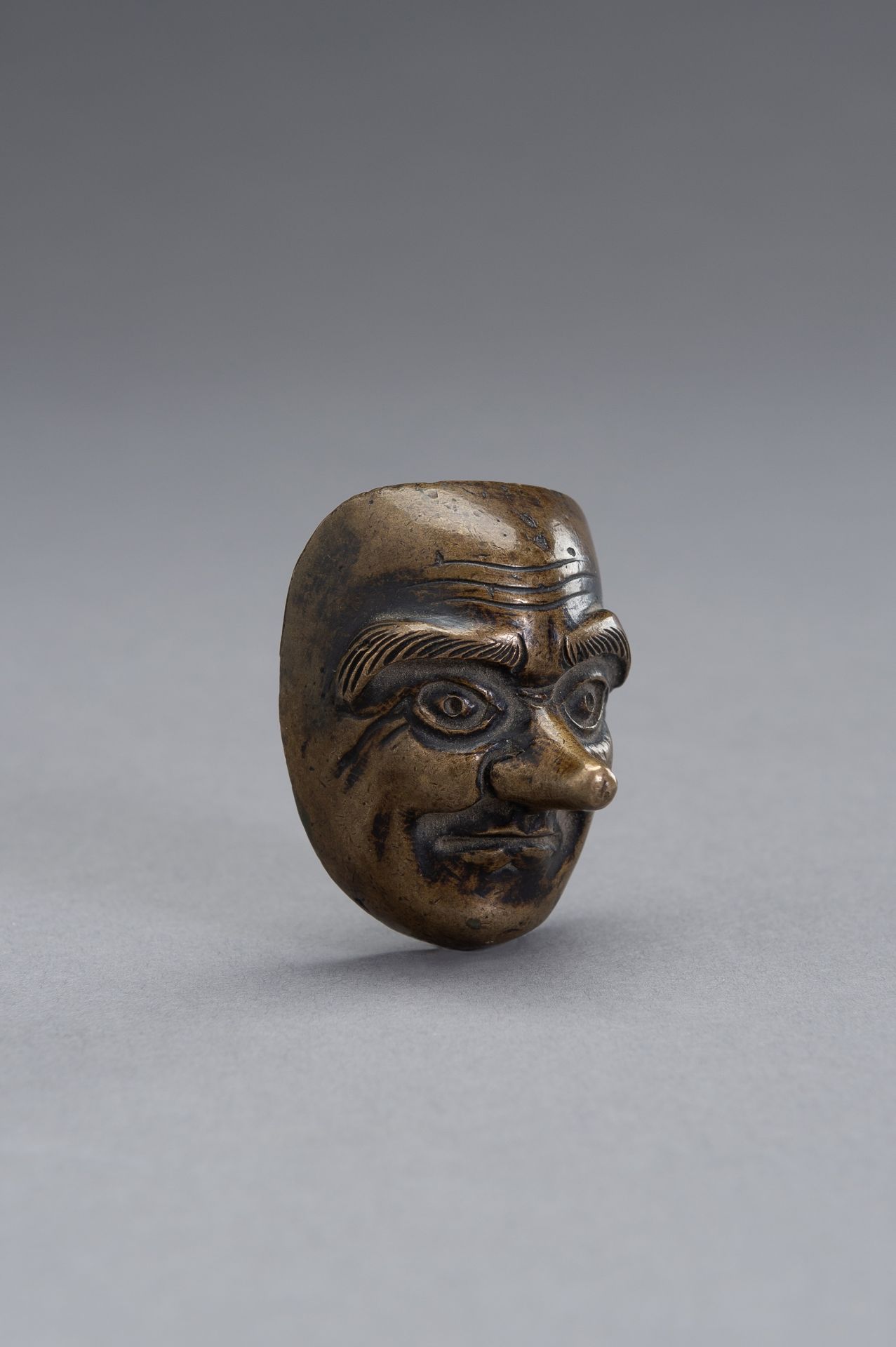 A BRONZE SCROLL WEIGHT IN THE SHAPE OF A NOH MASK