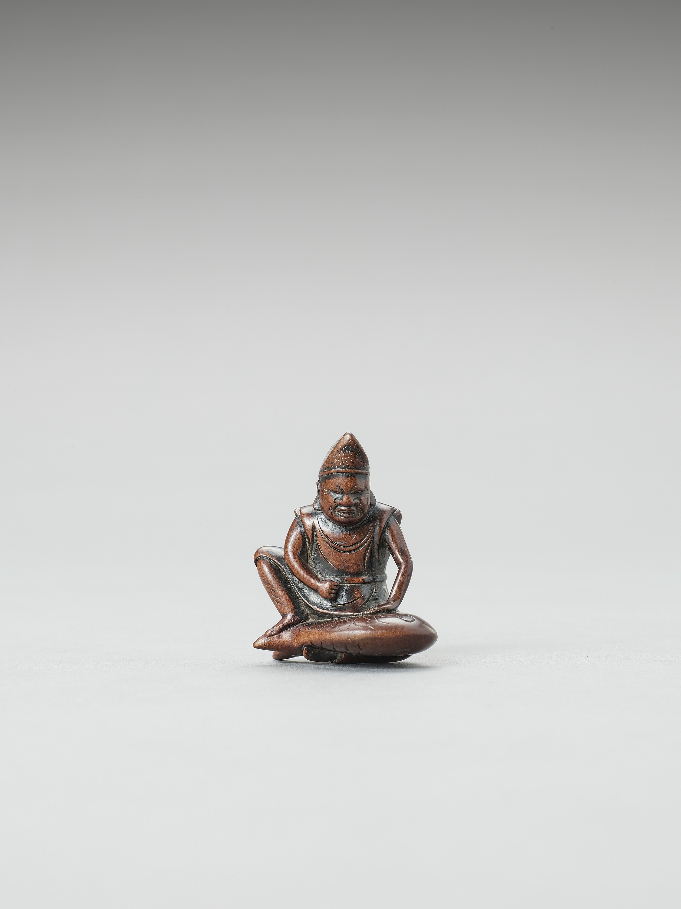 A WOOD NETSUKE OF EBISU SUBDUING A TAI FISH