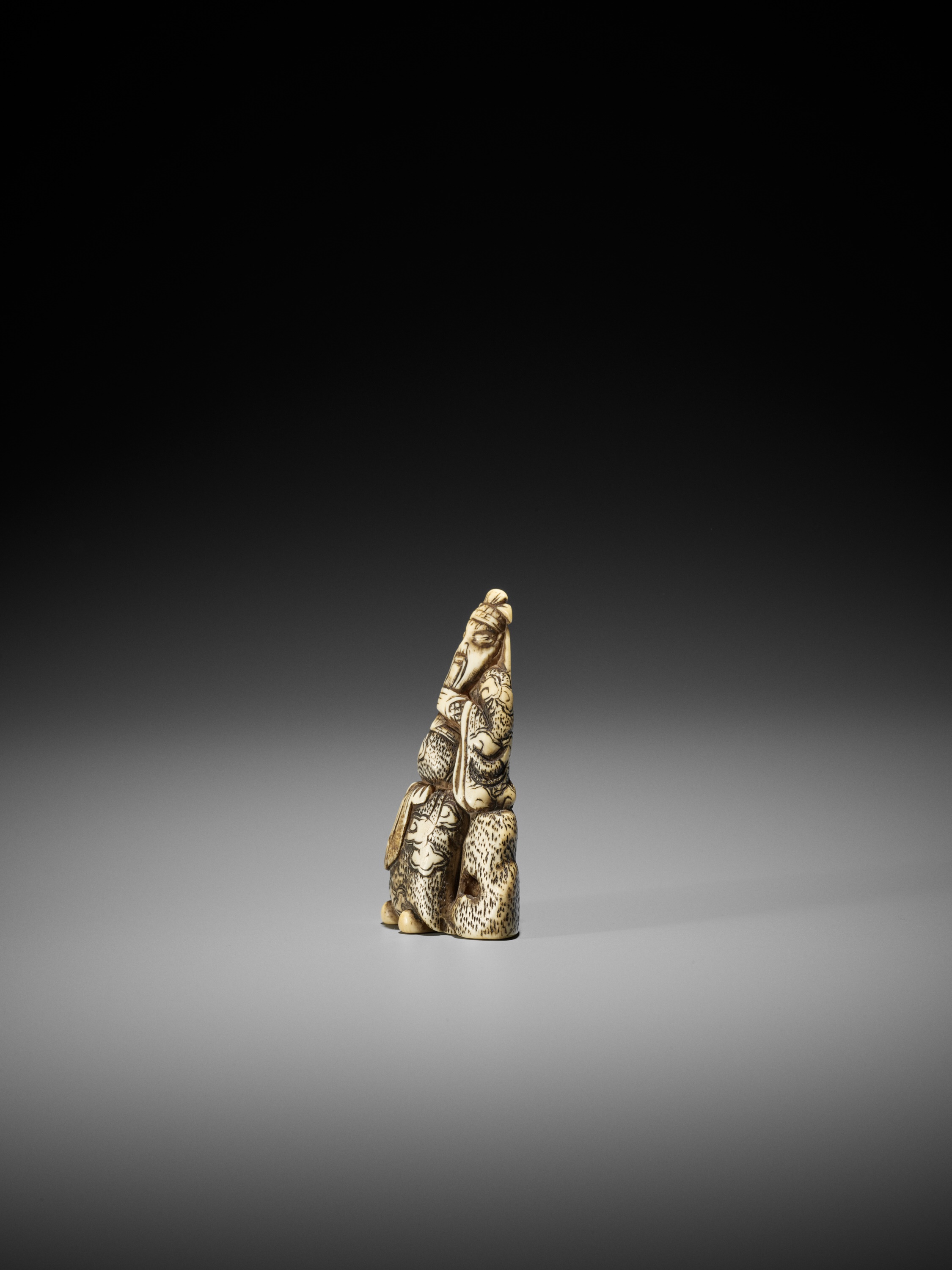 AN IVORY NETSUKE OF KAN'U LEANING AGAINST A ROCK - Image 6 of 8