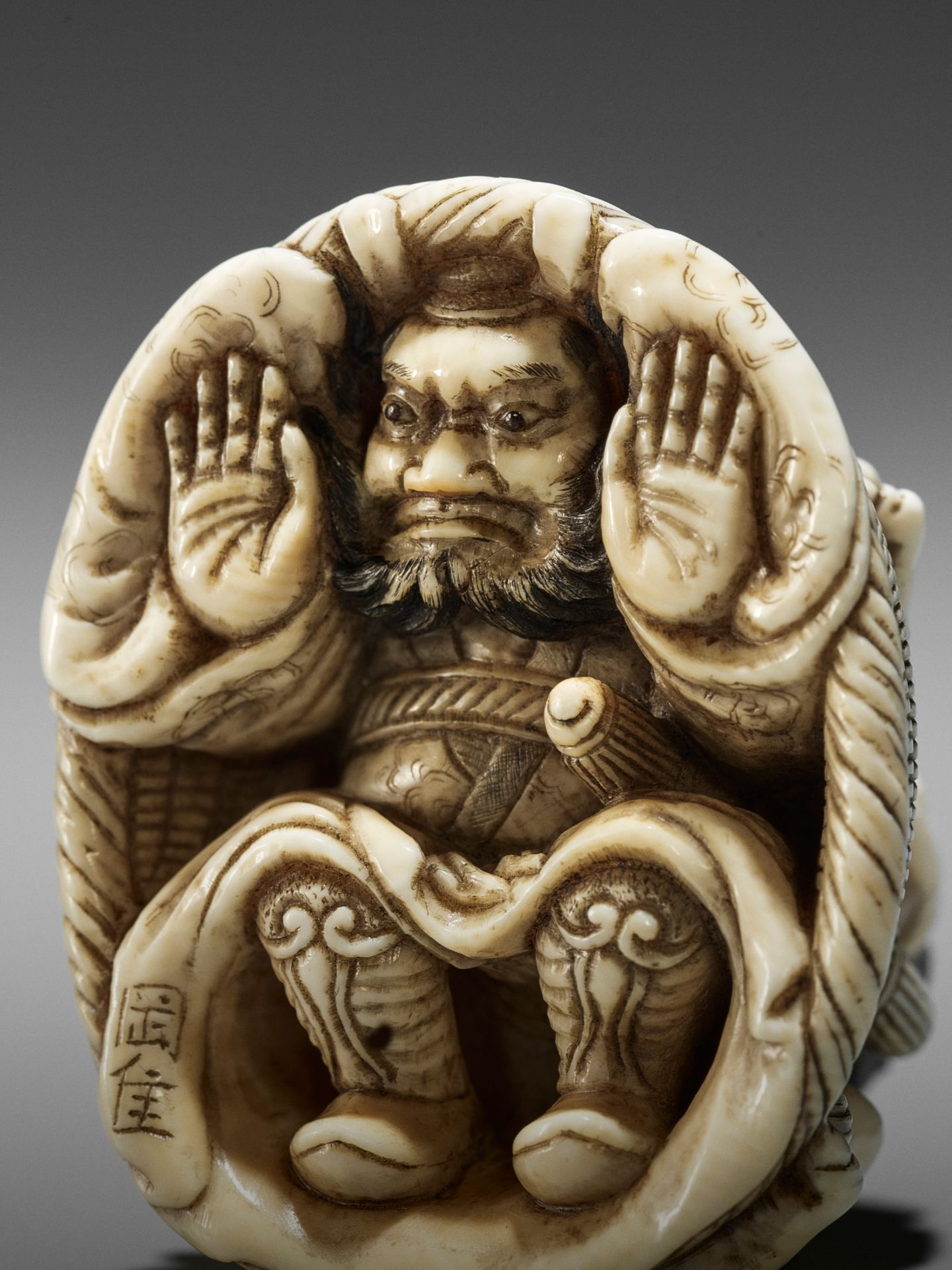 OKATORI: AN IVORY NETSUKE OF AN ONI TRAPPING SHOKI