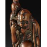 A TALL EARLY EDO SCHOOL WOOD NETSUKE OF IKKAKU SENNIN CARRYING THE LADY OF BENARES