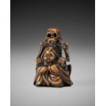 A WOOD NETSUKE OF A SKELETON MASSAGING OKAME, IN THE STYLE OF SHOKO