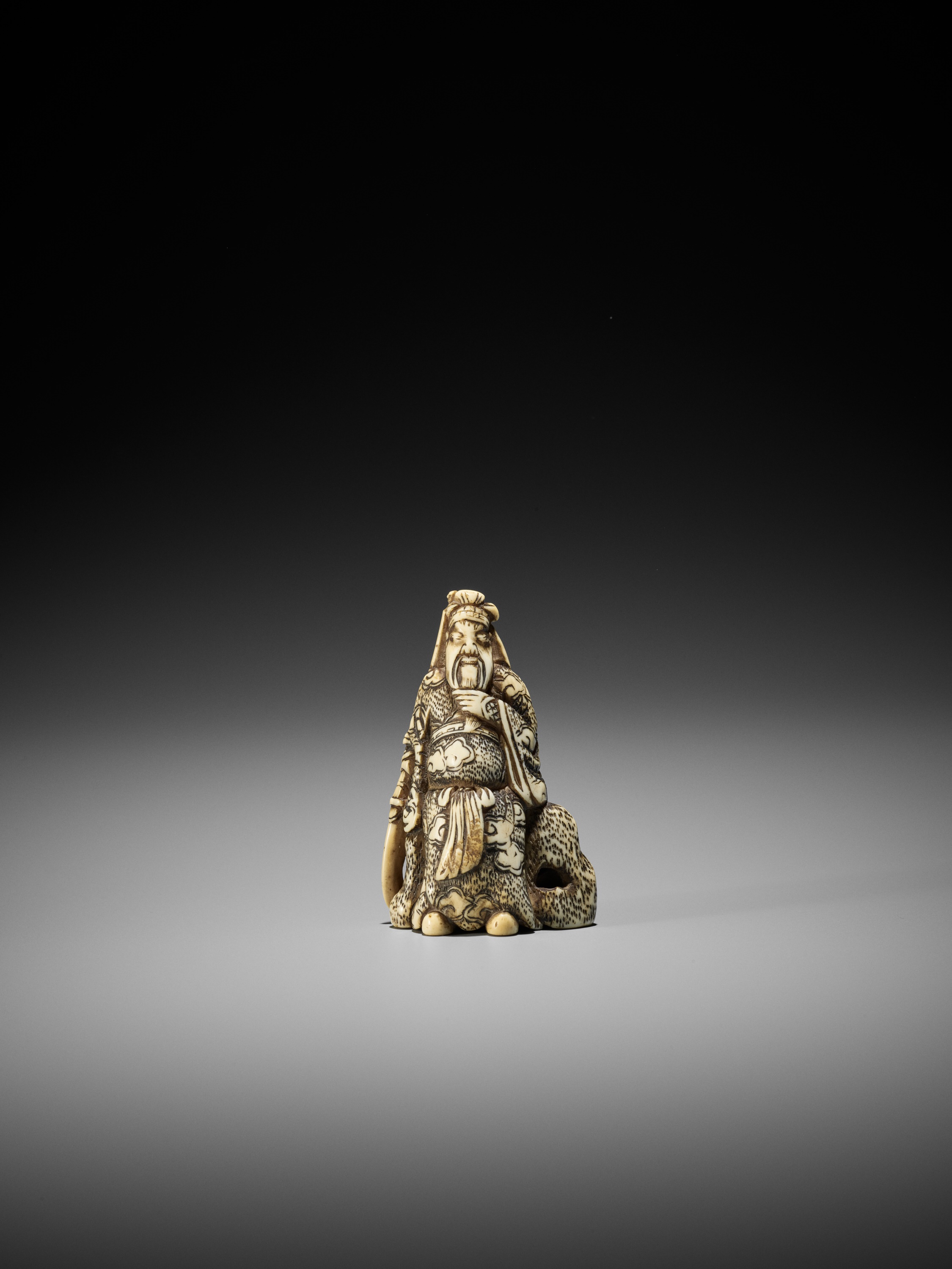 AN IVORY NETSUKE OF KAN'U LEANING AGAINST A ROCK - Image 2 of 8