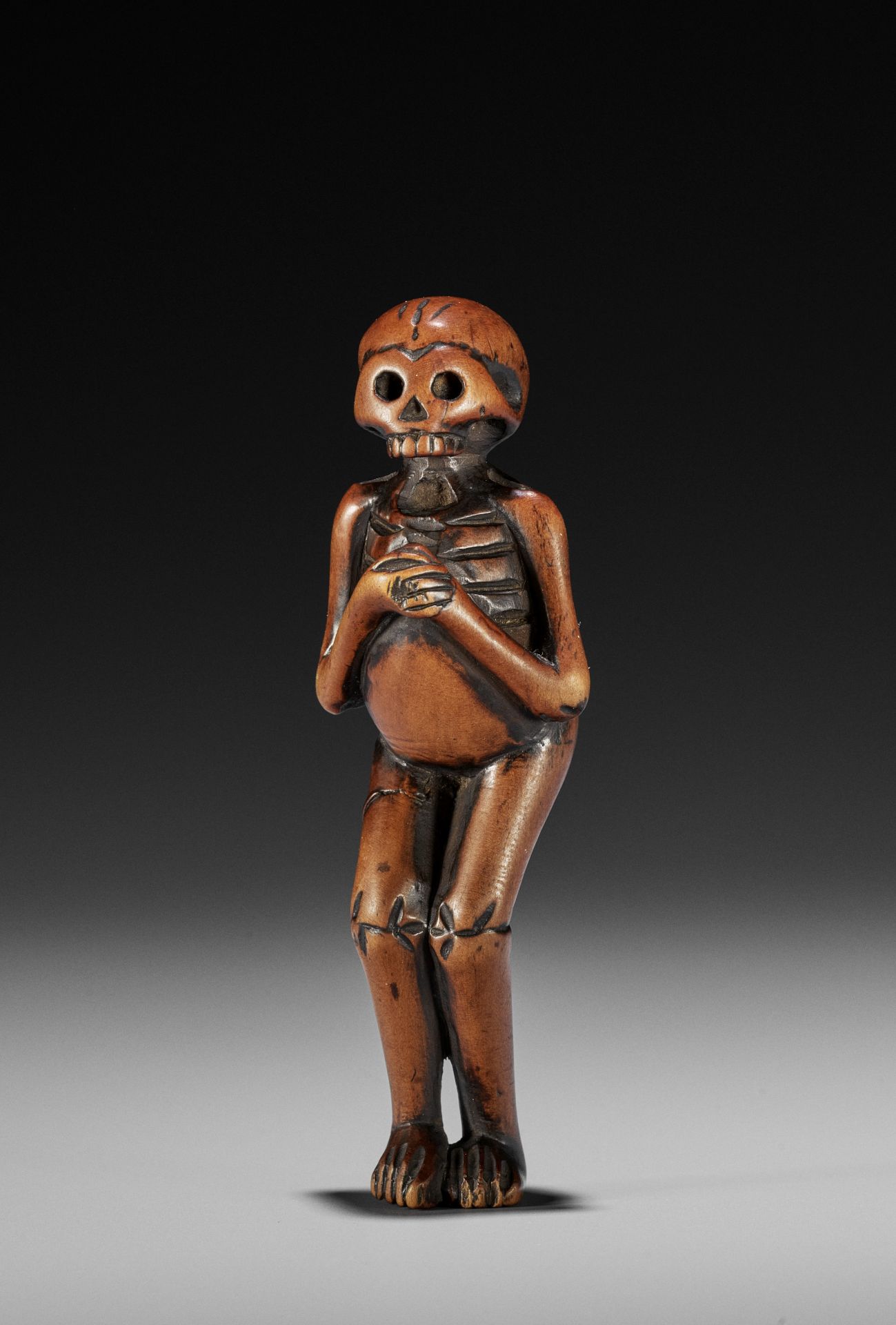 A RARE WOOD NETSUKE OF A SKELETON