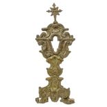 Monstrance in wood, covered with embossed brass relief, nineteenth century. H 44 cm.