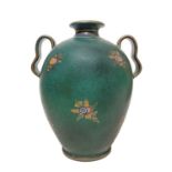 Majolica vase on green backfloor, with floral decorations.