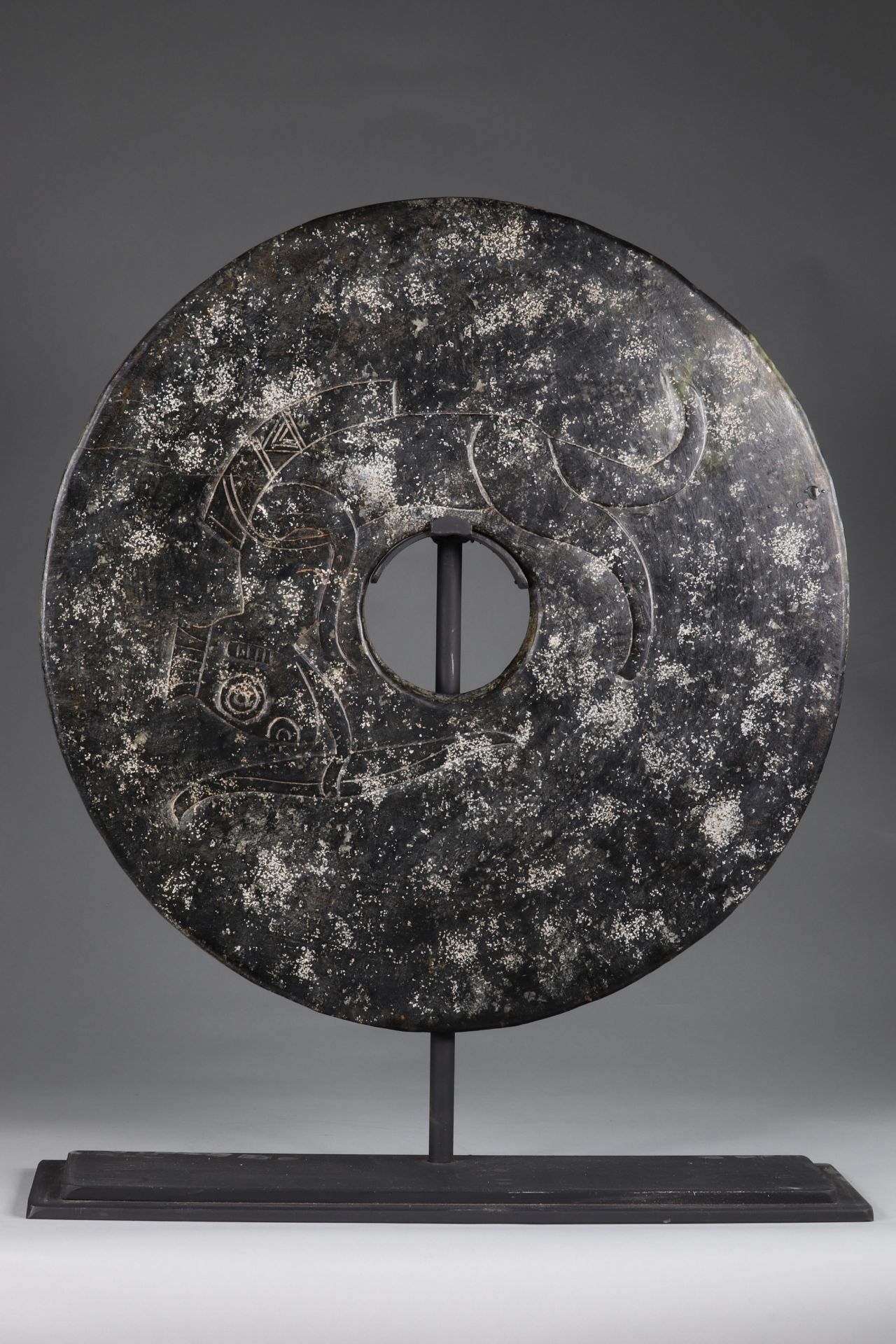 China Giant Bi-Disc, in black jade, decorated, in relief, with a fanciful animal, with human feature