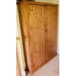 A 20th Century pine cupboards, moulded cornice above a pair of six plank panelled doors enclosing