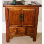 A Chinese elm collectors cabinet, moulded oversailing top, above two panel cupboards over three