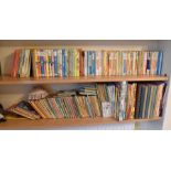 A collection of childrens books on 2 shelves to include Enid Blyton, Paddington, Ladybird, Rupert