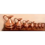 A set of seven gradual copper jugs; pair 20th century candlesticks (9)
