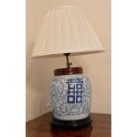 An oriental ginger jar on a wooden stand converted to a lamp.