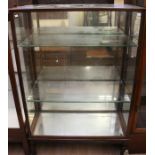 An early 20th Century mahogany shop display cabinet, fitted with two glass shelves, raised on square