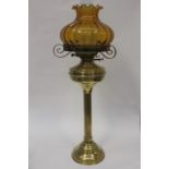 A brass Victorian style oil lamp with a double wick action, having an amber coloured glass shade,