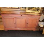 A contemporary solid beech pink stained sideboard, glass top, comprising three drawers over three