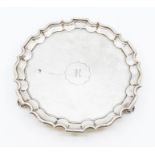 A silver round card tray, planish decoration with canted conerson, four scroll feet, diameter approx