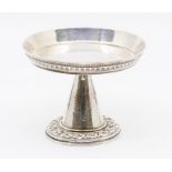 A Continental white metal tazza raised border, on ornate conical shaped base, the bordere chased