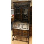 A George V Carolean style oak bureau bookcase, the upper section with two glazed doors enclosing